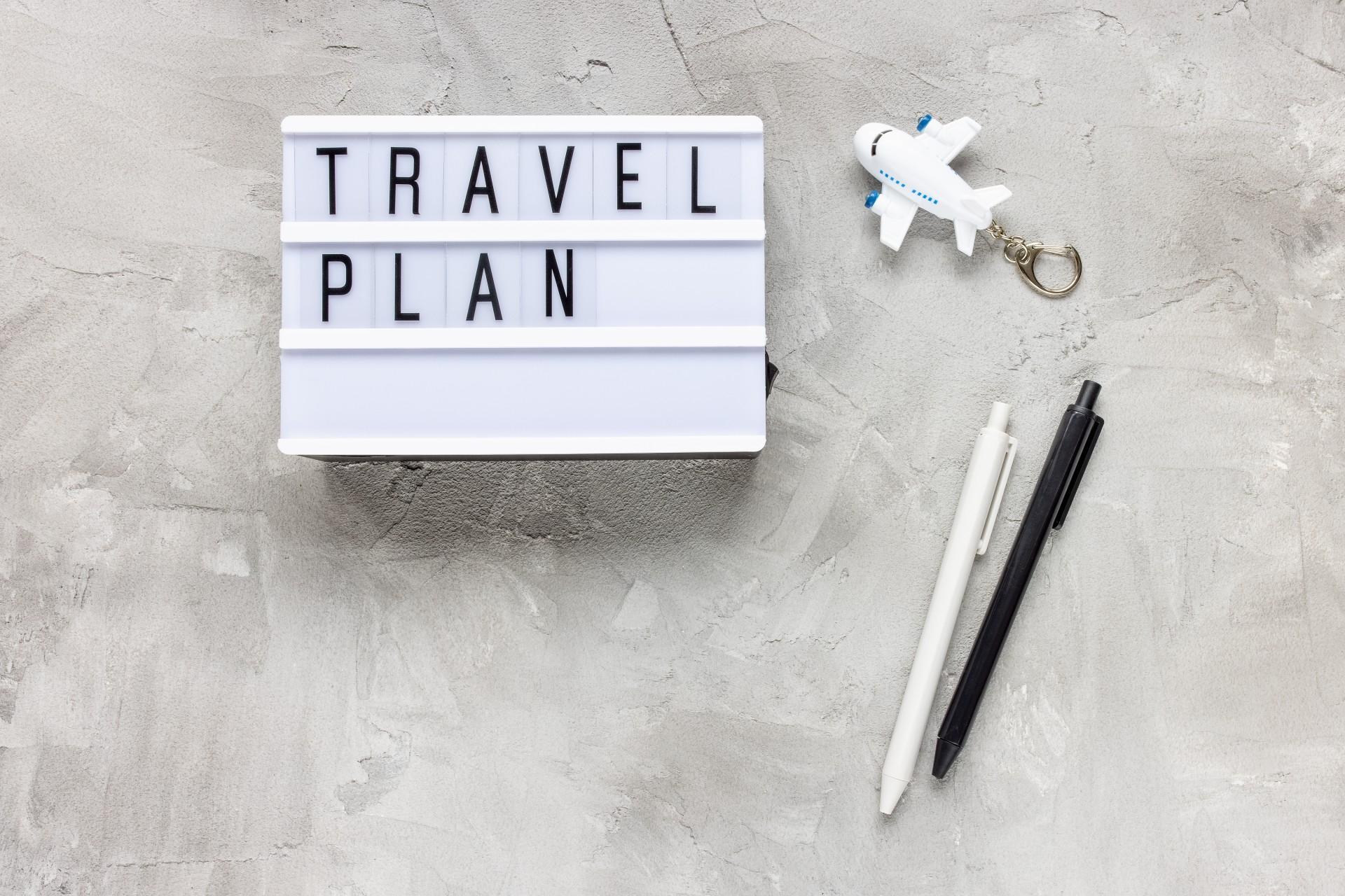 Words 'TRAVEL PLAN' displayed on a white plane background